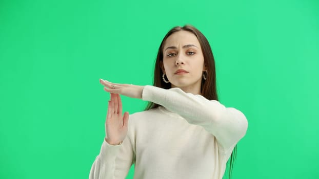 Woman, close-up, on a green background, showing a pause sign.