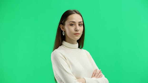 A woman, close-up, on a green background, crossed her arms.