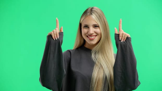 Woman, close-up, on a green background, pointing up.