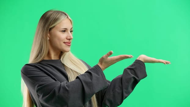 A woman, close-up, on a green background, points to the side.