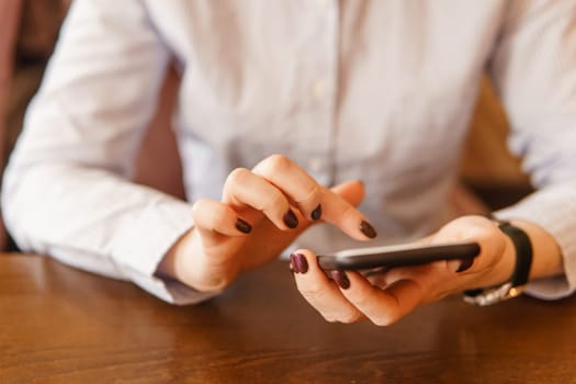 Mobile phone in female hands. Beautiful women's manicure