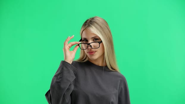 Woman, close-up, on a green background, wearing glasses.