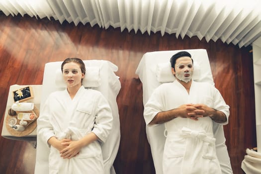 Serene modern daylight ambiance of spa salon, couple customer indulges in rejuvenating with facial skincare mask. Facial skin treatment and beauty cosmetology procedure for face. Quiescent