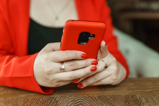 Mobile phone in female hands. Beautiful red women's manicure