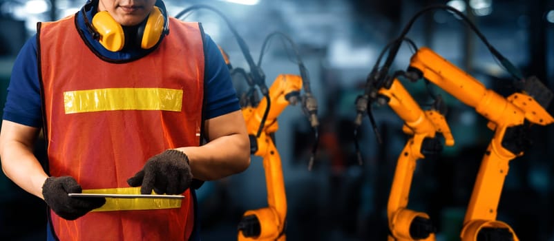 XAI Engineer use advanced robotic software to control industry robot arm in factory. Automation manufacturing process controlled by specialist using IOT software connected to internet network.