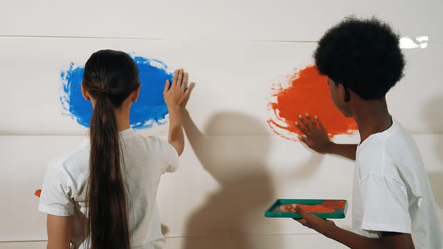 Diverse happy highschool girl and african boy paint the wall with water color in red and blue or contrast color by using their hands in art lesson. Colorful. Creative activity concept. Edification.