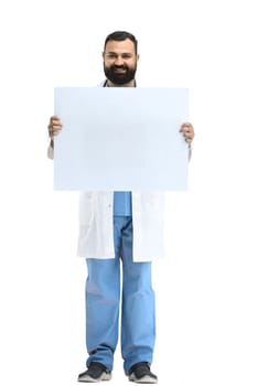 A male doctor, full-length, on a white background, shows a white sheet.