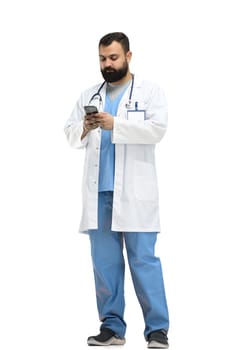 Male doctor, full-length, on a white background, with a phone.