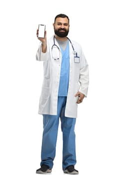 Male doctor, full-length, on a white background, with a phone.