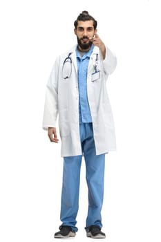 The male doctor, full-length, on a white background, points forward.