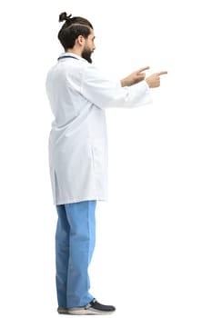 The male doctor, full-length, on a white background, points to the side.