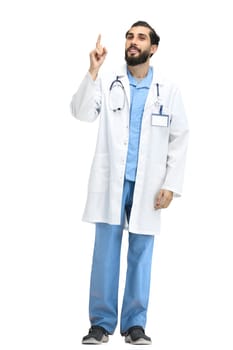The male doctor, full-length, on a white background, points up.