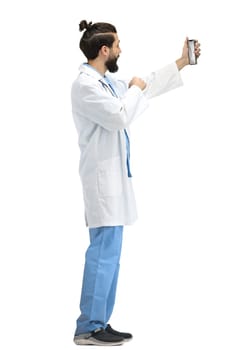 Male doctor, full-length, on a white background, with a phone.