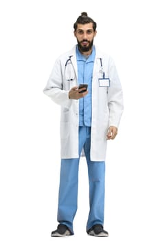 Male doctor, full-length, on a white background, with a phone.