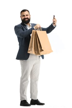 A man, full-length, on a white background, with bags and a phone.