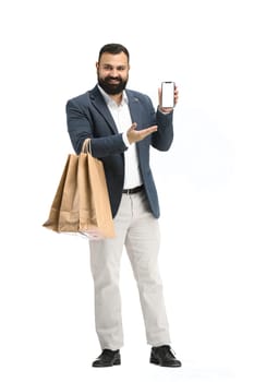 A man, full-length, on a white background, with bags and a phone.