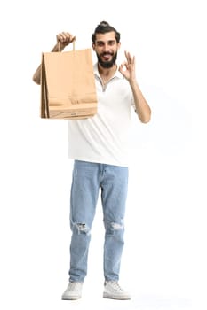 A man, full-length, on a white background, with bags, shows an ok sign.