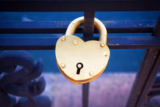 A heart shaped lock connected to other locks near Westminster bridge, Big Ben defocused in the background.