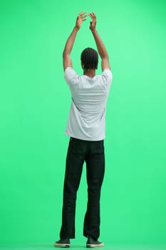 A man in a gray T-shirt, on a green background, in full height, claps.