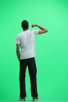 A man in a gray T-shirt, on a green background, in full height, rejoices.