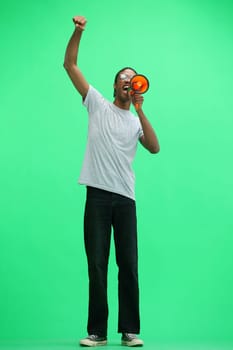 A man in a gray T-shirt, on a green background, full-length, with a megaphone.