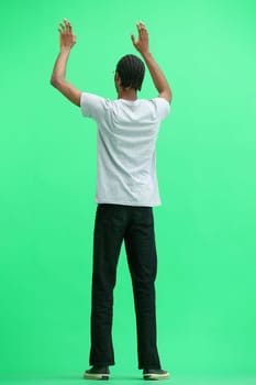 A man in a gray T-shirt, on a green background, standing tall, waving his arms.