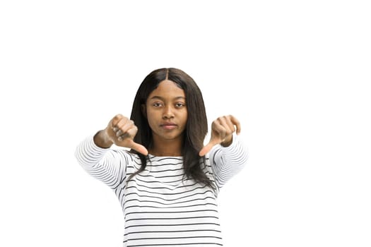 A woman, on a white background, in close-up, shows her thumbs down.