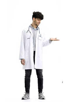 The male doctor, full-length, on a white background, points to the side.