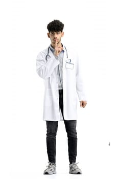A male doctor, full-length, on a white background, shows a sign of silence.