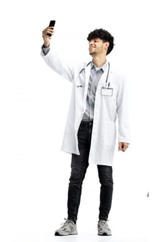 Male doctor, on a white background, full-length, with a phone.