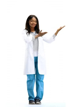 A female doctor, on a white background, in full height, points to the side.