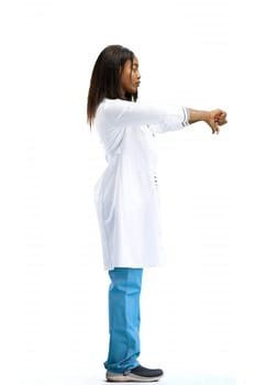 A female doctor, on a white background, in full height, shows her thumbs down.