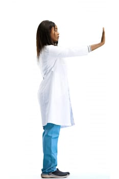 A female doctor, on a white background, in full height, shows a stop sign.