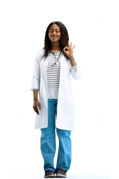 A female doctor, on a white background, in full height, shows the ok sign.