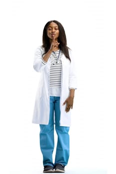 A full-length female doctor, on a white background, shows a sign of silence.