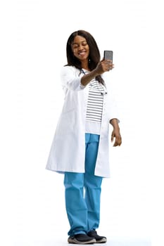 Female doctor, full-length, on a white background, with a phone.