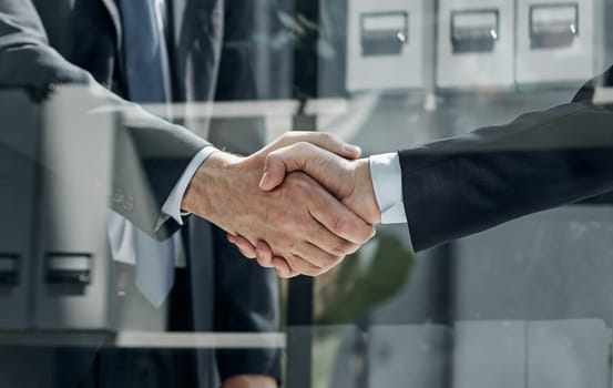 Two business people shaking hands in front of their colleagues