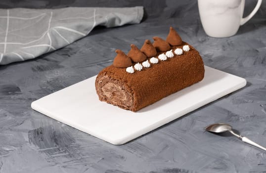 Chocolate roll on a white wooden cutting board.