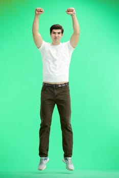 A man, full-length, on a green background, jumps.
