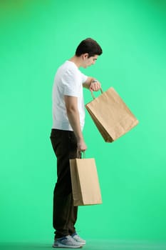 A man, full-length, on a green background, with bags.