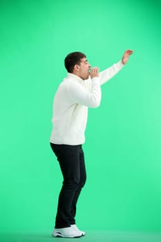 A man, full-length, on a green background, rejoices.