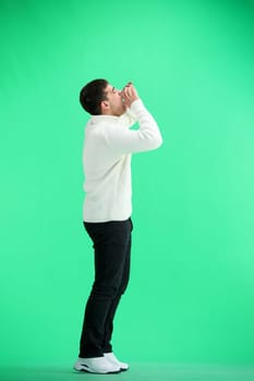 A man, full-length, on a green background, screams.