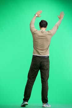 A man, full-length, on a green background, waving his arms.