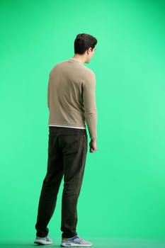 A man, full-length, on a green background.