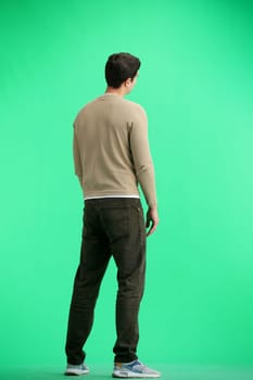 A man, full-length, on a green background.