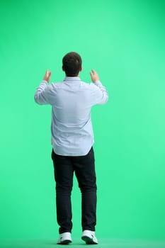 A man, full-length, on a green background, claps.