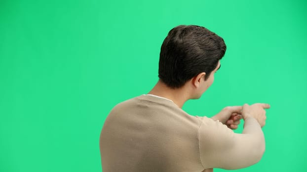 A man, close-up, on a green background, points forward.