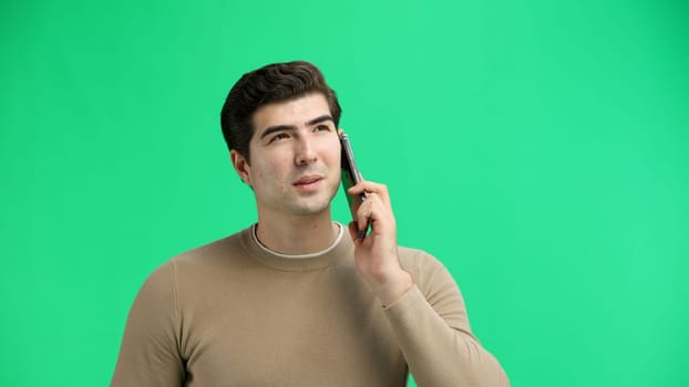 Man, close-up, on a green background, using a phone.
