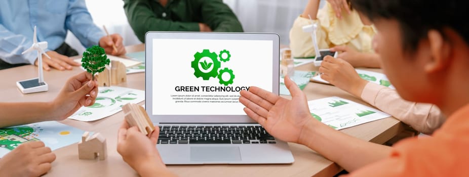 Green technology logo displayed on green business laptop while business team presenting green design to customer. ESG environment social governance and Eco conservative concept. Closeup. Delineation