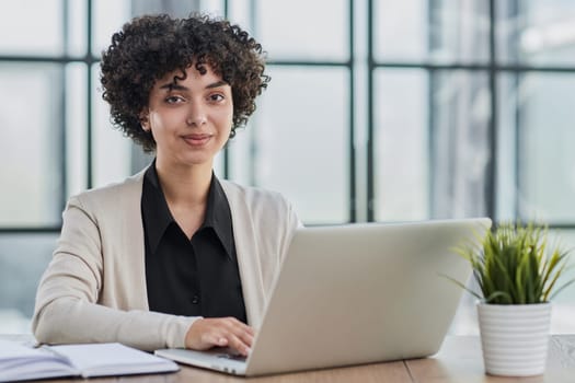 Image of young beautiful joyful woman smiling while working with laptop in office